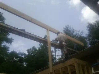 Carpenter setting a ridge beam over a new addition frame — Ice Dam Removal by Roofing Brothers in Spicer