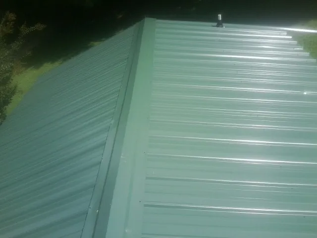 New green metal panels meeting at the ridge of a roof — Flat Roof Repair work by our crew in Spicer