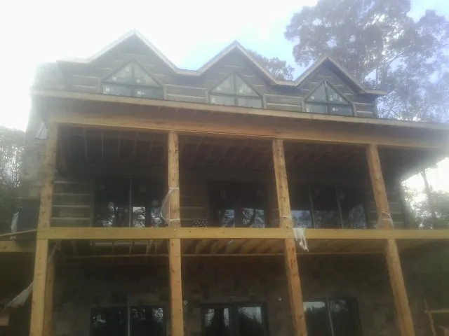 Dormers and porch framing on a large log home under construction — Roof Coating work by our crew in Spicer