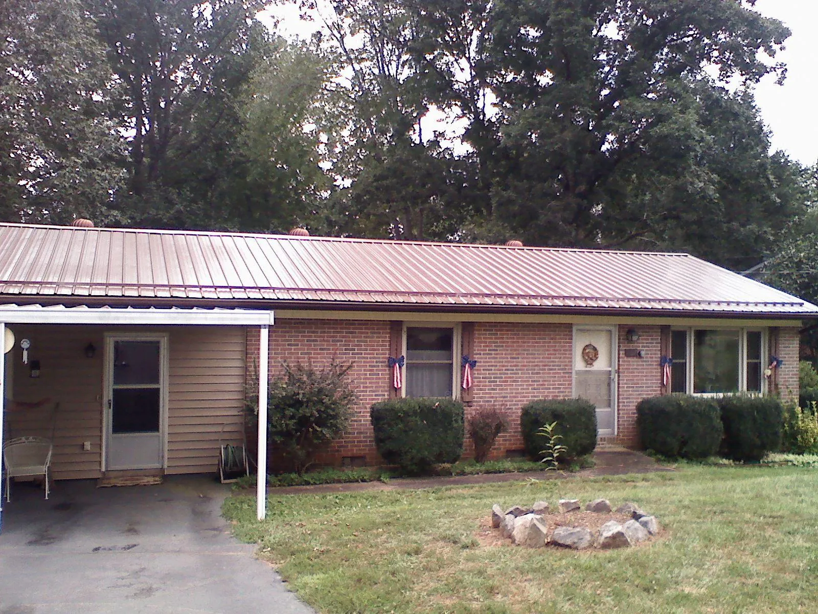 Bronze metal roof and carport on a brick ranch home — Roof Repair work by our crew in Spicer