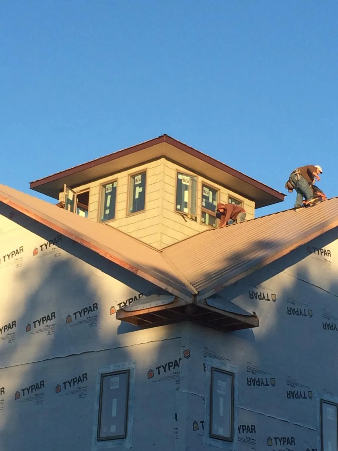 Roofers working around a rooftop cupola on a new metal roof at sunset — Roof Waterproofing in Spicer by Roofing Brothers